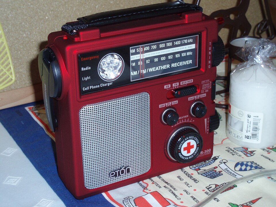 A red Eton emergency radio with a tuning dial, speaker grille and hand crank, for storm prep in Panama City, FL